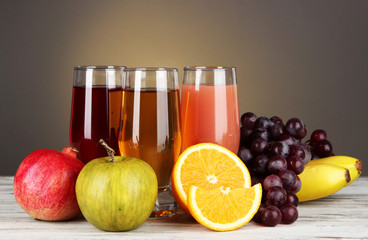 Glasses of fresh juice on table on gray background