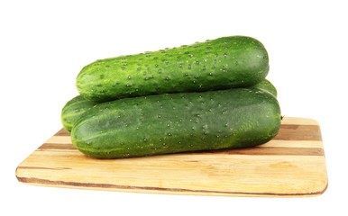 Tasty green cucumbers on wooden cutting board, isolated on