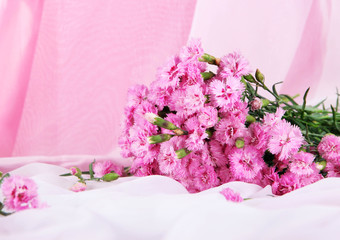 Many small pink cloves on light fabric background
