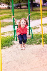 Beautiful little girl on a swings outdoor in the playground