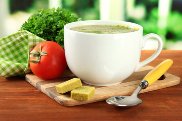 Cup of soup with bouillon cubes on wooden table