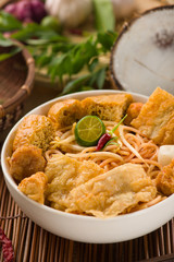 curry noodle malaysian penang style with raw ingredients on back