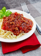 Spaghetti bolognese and green basil leaf on white plate