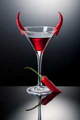 Glass of red martini decorated with chili pepper