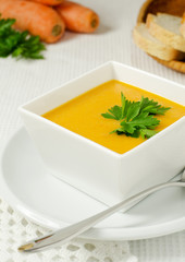 Carrot soup with parsley in white bowl