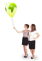 Happy ladies holding a green globe balloon