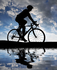 Obraz premium silhouette of the cyclist riding a road bike at sunset