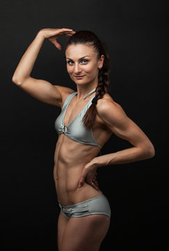 Young fitness woman in bikini flexing bicep