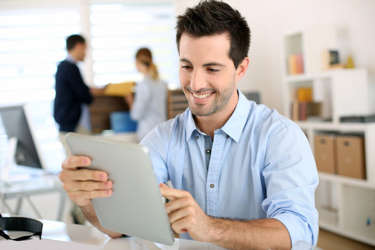 Smiling man in office working on digital tablet