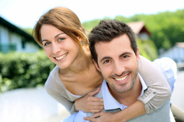 Cheerful couple standing in front of new house