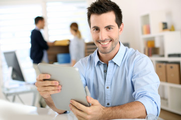 Smiling man in office working on digital tablet