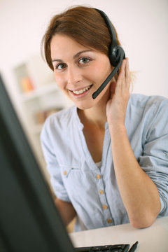 Young woman at work talking on phone with headset