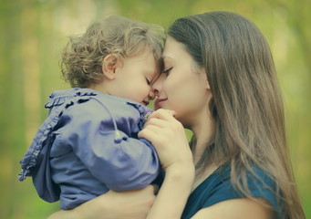 Happy loving mother and baby girl embracing outdoor summer backg