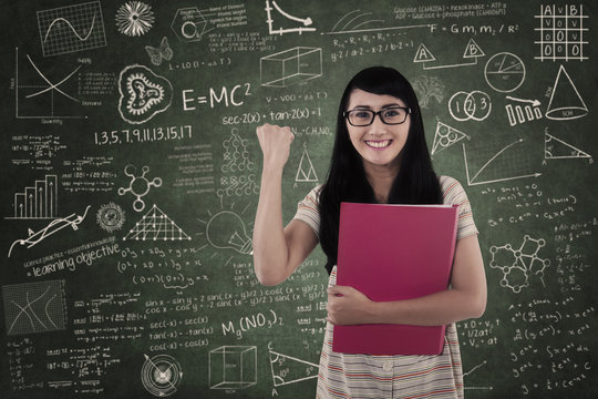 Happy female student in class on written board