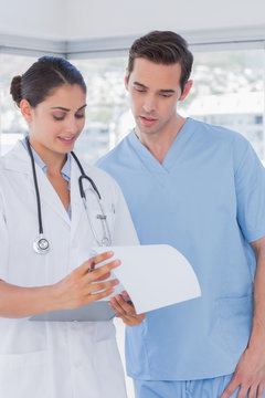 Doctor and surgeon reading over notes on clipboard