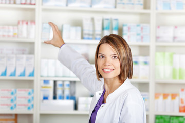 female pharmacist taking medicine from shelf