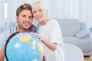 Father and his son looking at globe and smiling