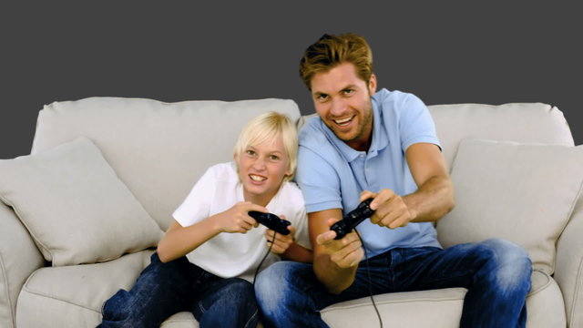 Father and son playing video games on grey background