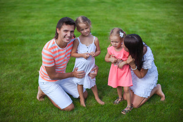 Fototapeta premium Portrait young family of four sit on the grass and have fun