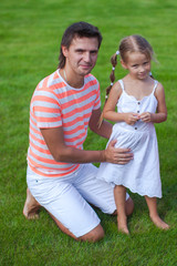 Portrat of father with his daughter sitting in the yard outdoors