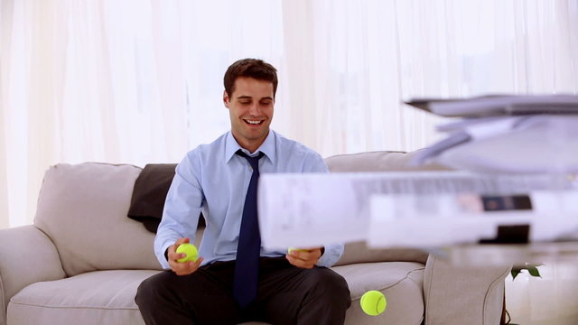 Happy businessman juggling with tennis ball