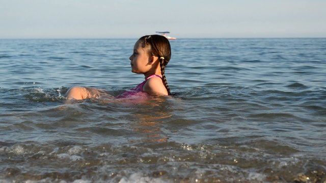 little girl swims in the sea