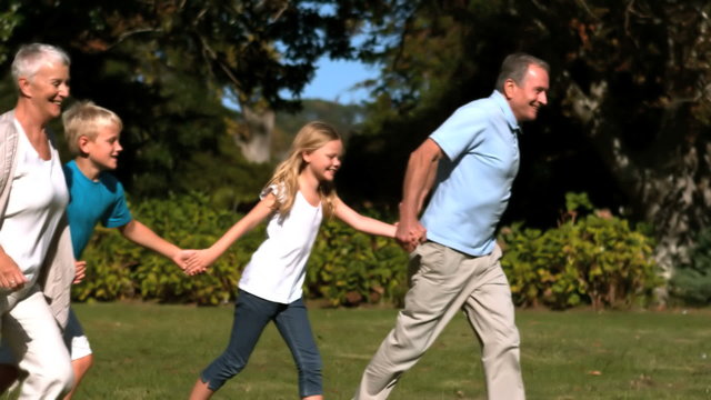 Grandchildren and grandparents running hand in hand in a park