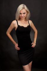 Fototapeta premium Beautiful girl in a short black dress on a black background.