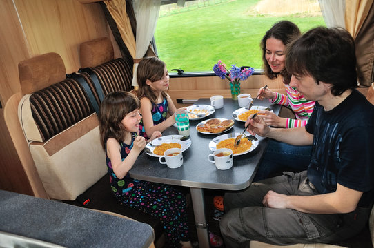 Family eating in RV interior, travel in camper on vacation