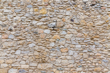 Rough, highly textured old stone block wall
