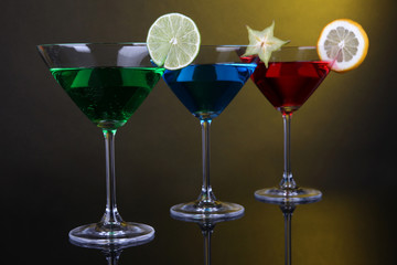 Alcoholic cocktails in martini glasses on dark yellow