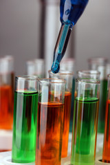 Laboratory pipette with drop of color liquid over glass test