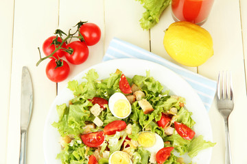 Caesar salad on white plate, on color wooden background