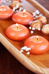 Beautiful candles in water on wooden table close-up