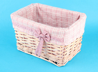 Wicket basket with pink fabric and bow, on color background