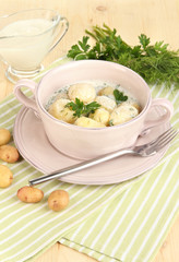 Tender young potatoes with sour cream and herbs in pan