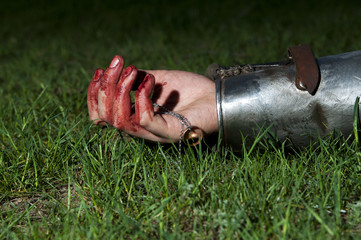 Bloody hand lying on the grass and holding ring