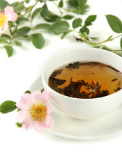 Cup of herbal tea with hip rose flowers, isolated on white