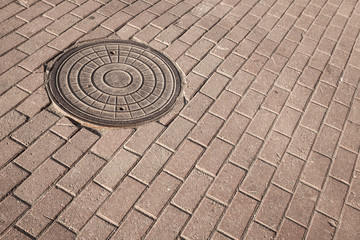 Fototapeta na wymiar Okrągły właz kanalizacyjny stali na chodniku