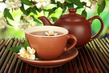 Cup of tea with jasmine, on bamboo mat, on bright background