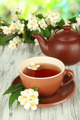 Cup of tea with jasmine, on wooden table, on bright background