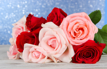 Beautiful bouquet of roses on table on blue background