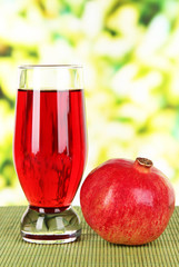 Glass of fresh garnet juice on table on bright background
