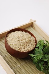 Raw brown rice in wooden bowl on white background