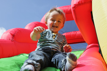 Naklejka premium Child on inflatable bouncy castle slide