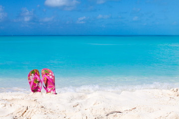 Pair of colored sandals on a white sand beach