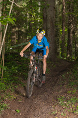 Fototapeta na wymiar Young cyclist riding downhill in forest