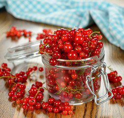 Fresh red currants in a glass jar on a brown table