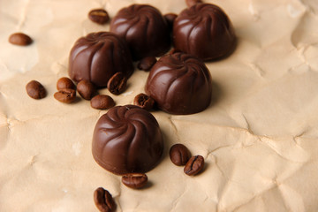 Chocolate candies and coffee beans, on beige paper background