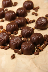 Chocolate candies and coffee beans, on beige paper background